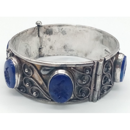 534 - AN ANTIQUE GREEK 800 SILVER HINGED BANGLE DECORATED WITH LAPIS LAZULI STONES . 61.2gms