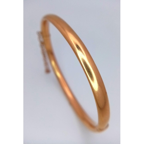 228 - A 9K GOLD BANGLE WITH SAFETY CHAIN.  9.9gms