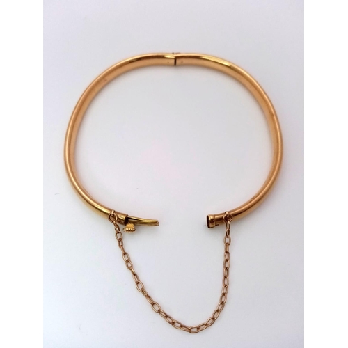 228 - A 9K GOLD BANGLE WITH SAFETY CHAIN.  9.9gms