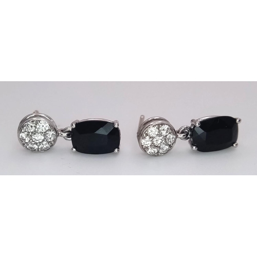 1229 - A Pair of 18K Diamond and Onyx Earrings. Diamond clusters and rectangular cut onyx. No backs. With c... 