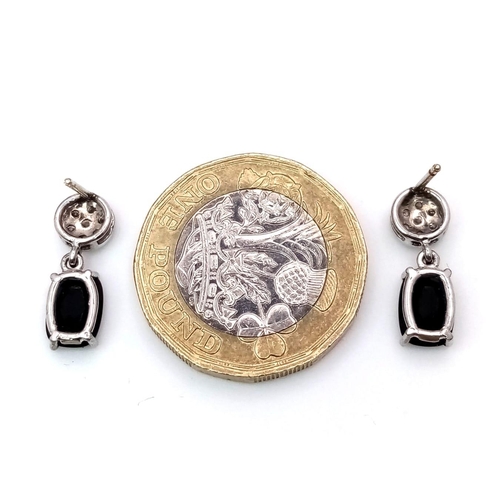 1229 - A Pair of 18K Diamond and Onyx Earrings. Diamond clusters and rectangular cut onyx. No backs. With c... 