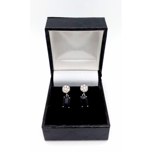 1229 - A Pair of 18K Diamond and Onyx Earrings. Diamond clusters and rectangular cut onyx. No backs. With c... 