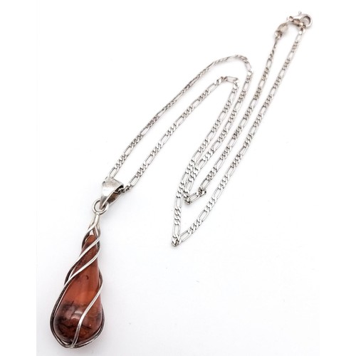 1026 - A MODERN DESIGN SILVER AND AMBER PENDANT ON A 42cms SILVER CHAIN .  6.8gms