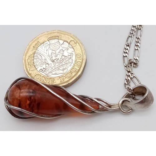 1026 - A MODERN DESIGN SILVER AND AMBER PENDANT ON A 42cms SILVER CHAIN .  6.8gms