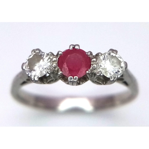 340 - A Vintage Platinum Diamond and Ruby Ring. A central ruby with two brilliant round cut diamonds. Size... 