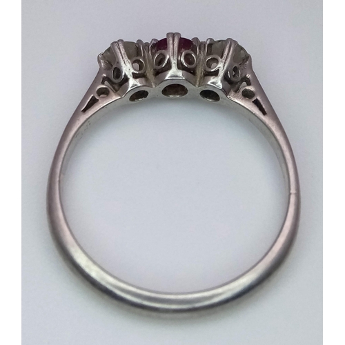 340 - A Vintage Platinum Diamond and Ruby Ring. A central ruby with two brilliant round cut diamonds. Size... 