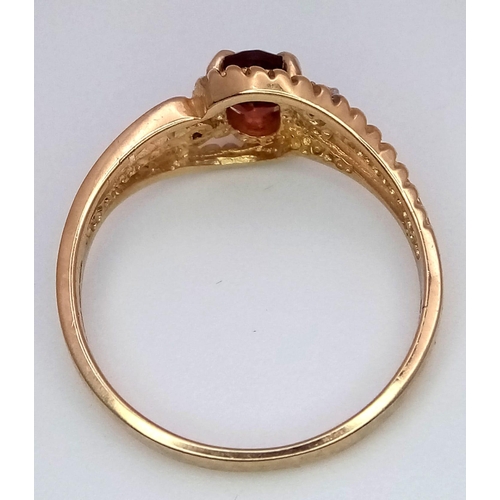 85 - A 10k Yellow Gold Garnet and Diamond Crossover Ring. Size L. 1.86g weight.