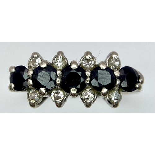 26 - A Classic Vintage Sapphire and Diamond Ring. Five sapphires between four two rows of diamonds. Size ... 