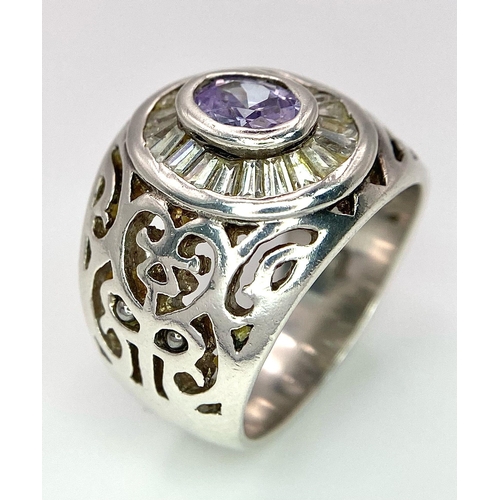 800 - A 925 Silver and Amethyst Ring. Central amethyst with white stone surround. Pierced decoration. Size... 