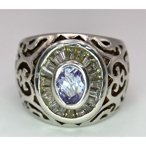 800 - A 925 Silver and Amethyst Ring. Central amethyst with white stone surround. Pierced decoration. Size... 