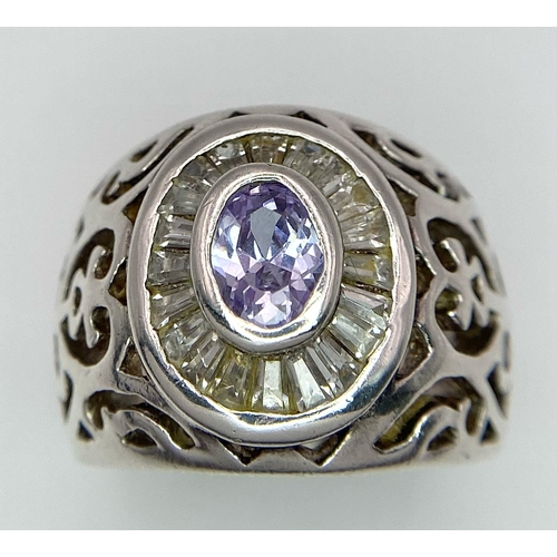 800 - A 925 Silver and Amethyst Ring. Central amethyst with white stone surround. Pierced decoration. Size... 