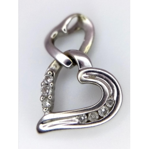 1322 - A 9K WHITE GOLD DOUBLE HEART DIAMOND SET PENDANT. 1.6G