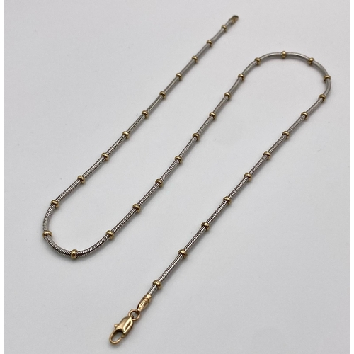 1673 - A 9k white gold chain with yellow gold ball detailing. (16