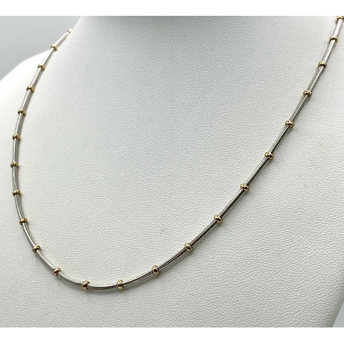 1673 - A 9k white gold chain with yellow gold ball detailing. (16