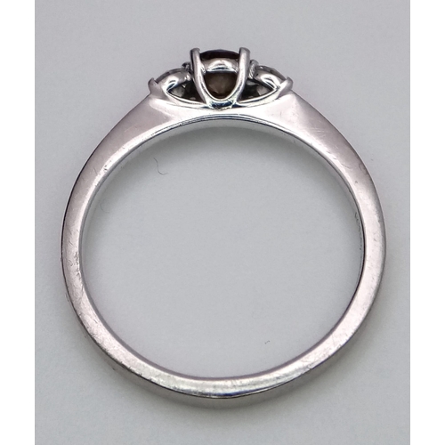 1574 - A Browns Designer 18K White Gold and Diamond Trilogy Ring. Central brilliant round cut 0.30ct champa... 