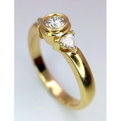 246 - An 18K Yellow Gold Diamond Ring. Central round cut diamond with trillion cut diamond accents. Size M... 