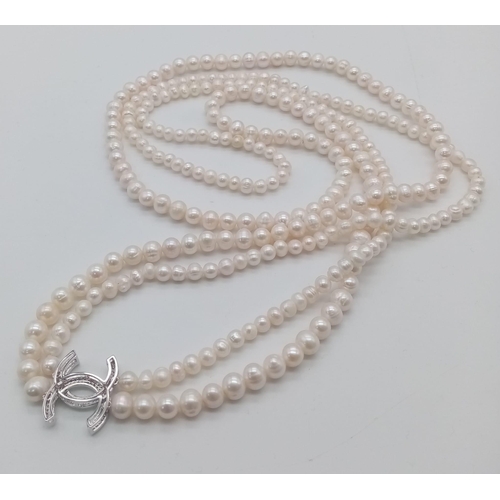 410 - A Long Double Row Cultured Pearl Necklace with a Silver CC Clasp. 80cm length.