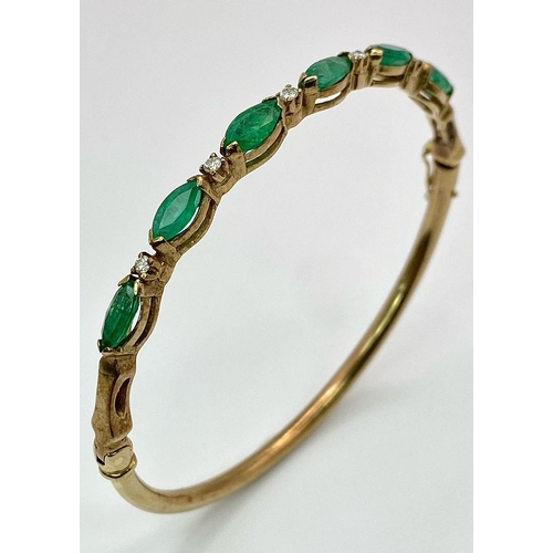 34 - A 9K Yellow Gold Emerald and Diamond Bangle. Six oval cut emeralds with five brilliant round cut dia... 