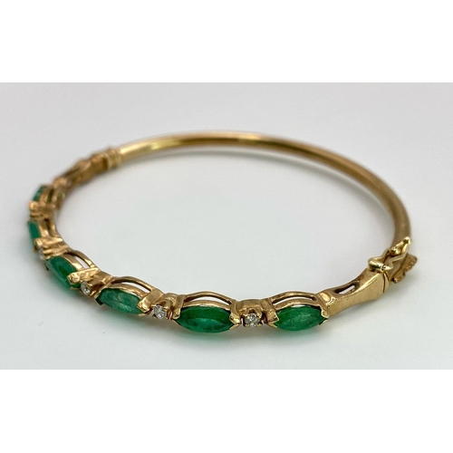 34 - A 9K Yellow Gold Emerald and Diamond Bangle. Six oval cut emeralds with five brilliant round cut dia... 