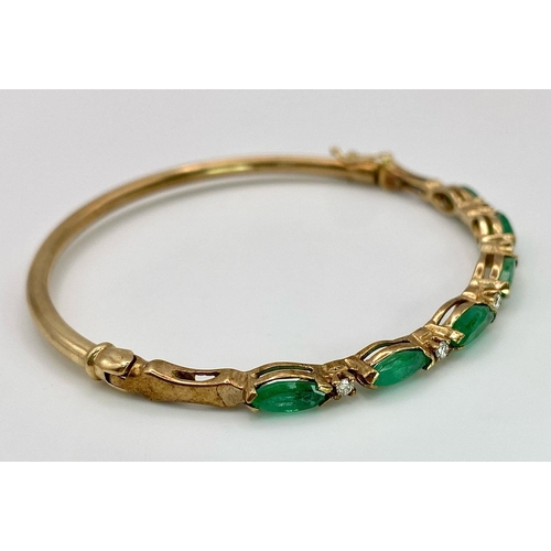 34 - A 9K Yellow Gold Emerald and Diamond Bangle. Six oval cut emeralds with five brilliant round cut dia... 