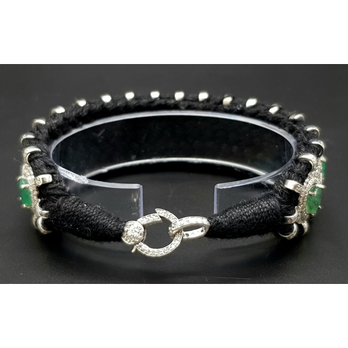 12 - An Asian Inspired Emerald and Diamond Bracelet set in a Woven Black Textile. 10ctw of oval cut emera... 