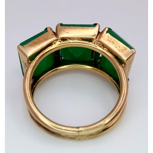 526 - A TRILOGY OF TOP QUALITY EMERALDS SET IN A STYLISH 14K GOLD SETTING.  6.7gms    size M