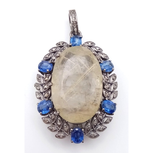 505 - A 26ct Rutilated Quartz Gemstone Pendant with 2.50ctw Kyanite Surround. Set in 925 silver. 4.5cm. 12... 