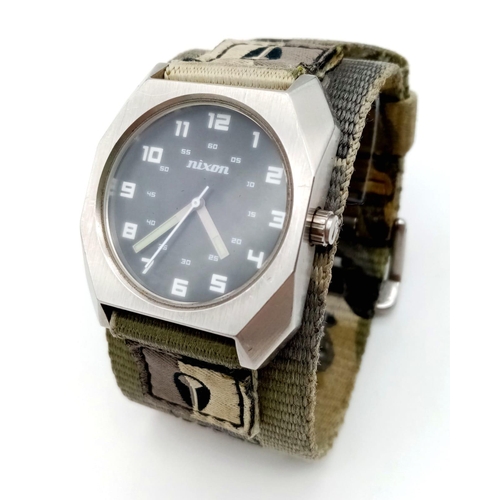 1398 - A Men’s Nixon Military Watch. 38mm Including Crown on Camouflage Combat Strap. Scout Model. Full Wor... 