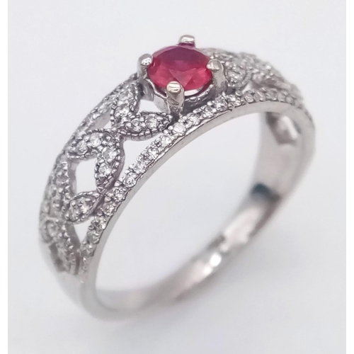 1200 - A 9K WHITE GOLD RING ENCRUSTED WITH DIAMONDS AND WITH A RUBY CENTRE STONE .   2.5gms   size N