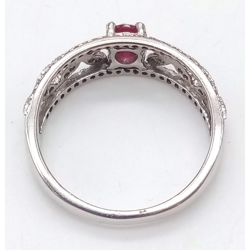 1200 - A 9K WHITE GOLD RING ENCRUSTED WITH DIAMONDS AND WITH A RUBY CENTRE STONE .   2.5gms   size N