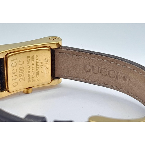 1411 - A Gucci 2300L Quartz Ladies Watch. Brown leather strap. Gilded case - 17mm. White dial. In need of a... 