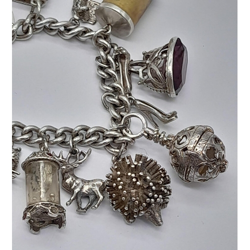 1450 - A SILVER CHARM BRACELET WITH 17 VERY COLLECTABLE CHARMS TO INCLUDE HEDGEHOG , BUTTERFLY , TEA POT , ... 