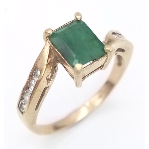 1246 - A 1ct EMERALD IN A 9K GOLD RING WITH WHITE SAPPHIRE SHOULDERS .  2.6gms   size O