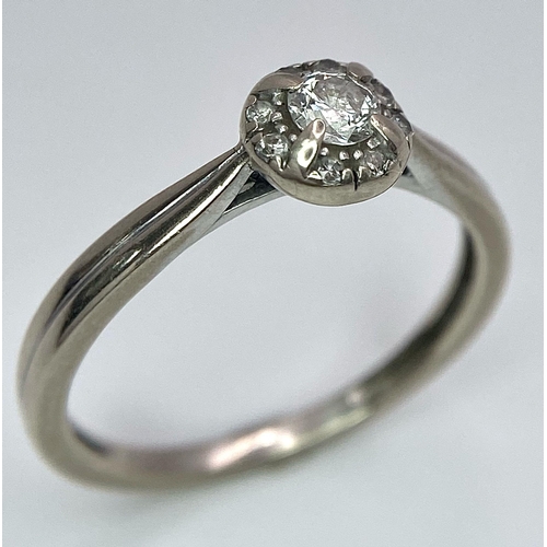 1677 - A 9K White Gold Diamond Ring. Central 0.16ct stone with smaller diamond surround. Size L. 1.86g tota... 