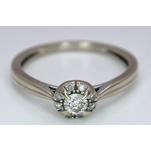 1677 - A 9K White Gold Diamond Ring. Central 0.16ct stone with smaller diamond surround. Size L. 1.86g tota... 