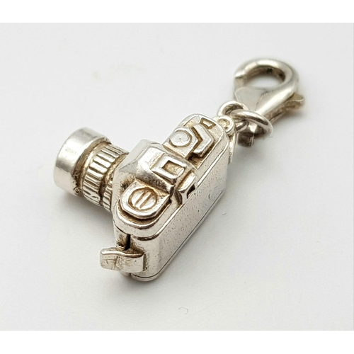 1265 - A STERLING SILVER CAMERA CHARM WHICH OPENS TO REVEAL A COUPLE HOLDING HANDS 5.1G

ref: SC 3127