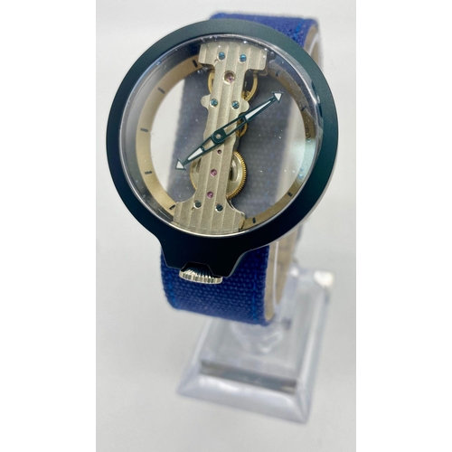 869 - A Verticale Mechanical Top Winder Gents Watch. Denim blue textile strap. Black ceramic gilded skelet... 