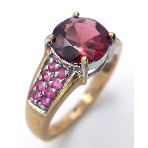 624 - A 9K Yellow Gold Garnet and Ruby Ring. Central garnet with ruby accents. Size K. 3.05g total weight.