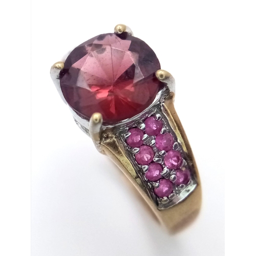 624 - A 9K Yellow Gold Garnet and Ruby Ring. Central garnet with ruby accents. Size K. 3.05g total weight.