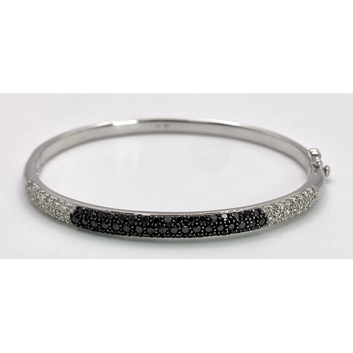 1030 - AN 18K WHITE GOLD BANGLE WITH BLACK AND WHITE QUALITY DIAMONDS.  17.3gms