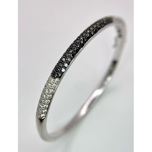 1030 - AN 18K WHITE GOLD BANGLE WITH BLACK AND WHITE QUALITY DIAMONDS.  17.3gms