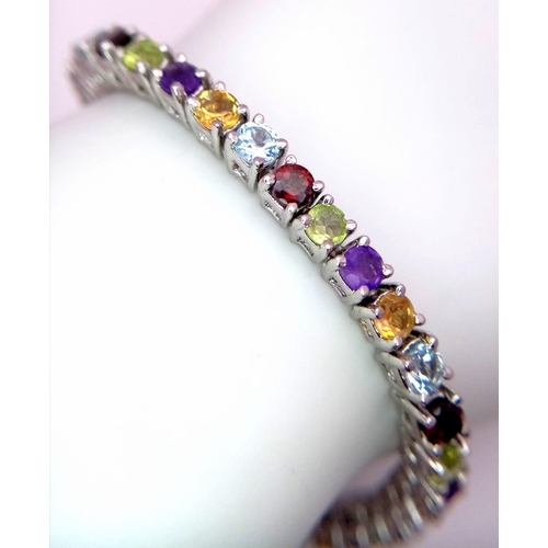 569 - A Multi-gemstone Tennis Bracelet set in 925 Silver. Amethyst Citrine, Topaz and Peridot. 18cm length... 