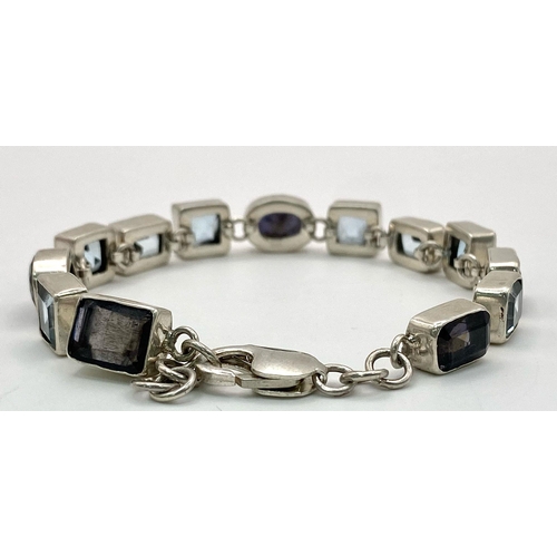 935 - A Blue Topaz and Iolite Tennis Bracelet set in 925 Sterling Silver. 51ctw. W-25.5g. 20cm length. Ref... 