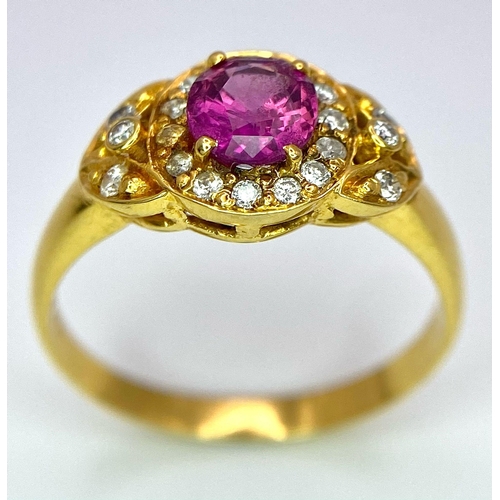 45 - An 18K Yellow Gold Pink Sapphire and Diamond Ring. Central oval sapphire with diamond halo and diamo... 