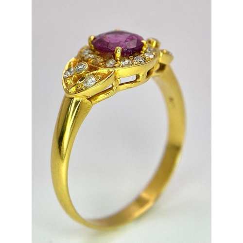 45 - An 18K Yellow Gold Pink Sapphire and Diamond Ring. Central oval sapphire with diamond halo and diamo... 