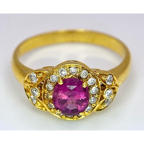 45 - An 18K Yellow Gold Pink Sapphire and Diamond Ring. Central oval sapphire with diamond halo and diamo... 