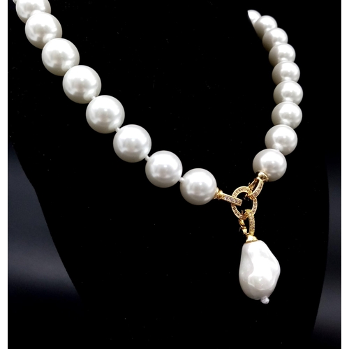 687 - A Baroque Shaped Pearl Shell Pendant on a South Sea White Pearl Shell Necklace. Gilded clasps and wh... 