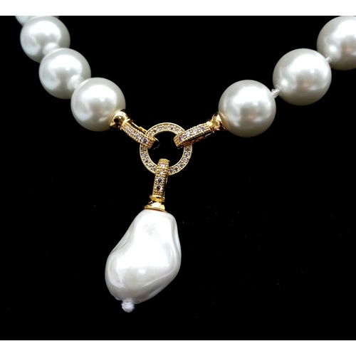 687 - A Baroque Shaped Pearl Shell Pendant on a South Sea White Pearl Shell Necklace. Gilded clasps and wh... 