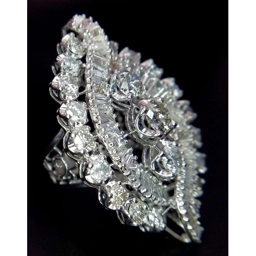 350 - An 18K White Gold Diamond Dress Ring. This 'all seeing' diamond masterpiece begins with three centra... 