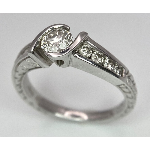 19 - An 18K White Gold Diamond Crossover Ring. 0.50ct tinted brilliant round cut diamond with eight round... 